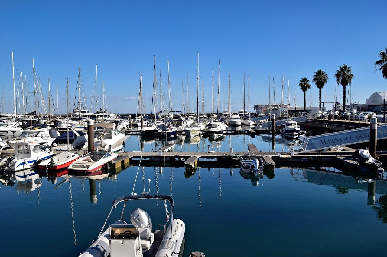 Yachts and sailboats docked at a Mediterranean marina under blue sky